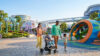Une famille heureuse se promène avec un bébé en poussette et un jeune enfant dans le parc futuriste du Futuroscope.