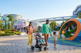 Une famille heureuse se promène avec un bébé en poussette et un jeune enfant dans le parc futuriste du Futuroscope.